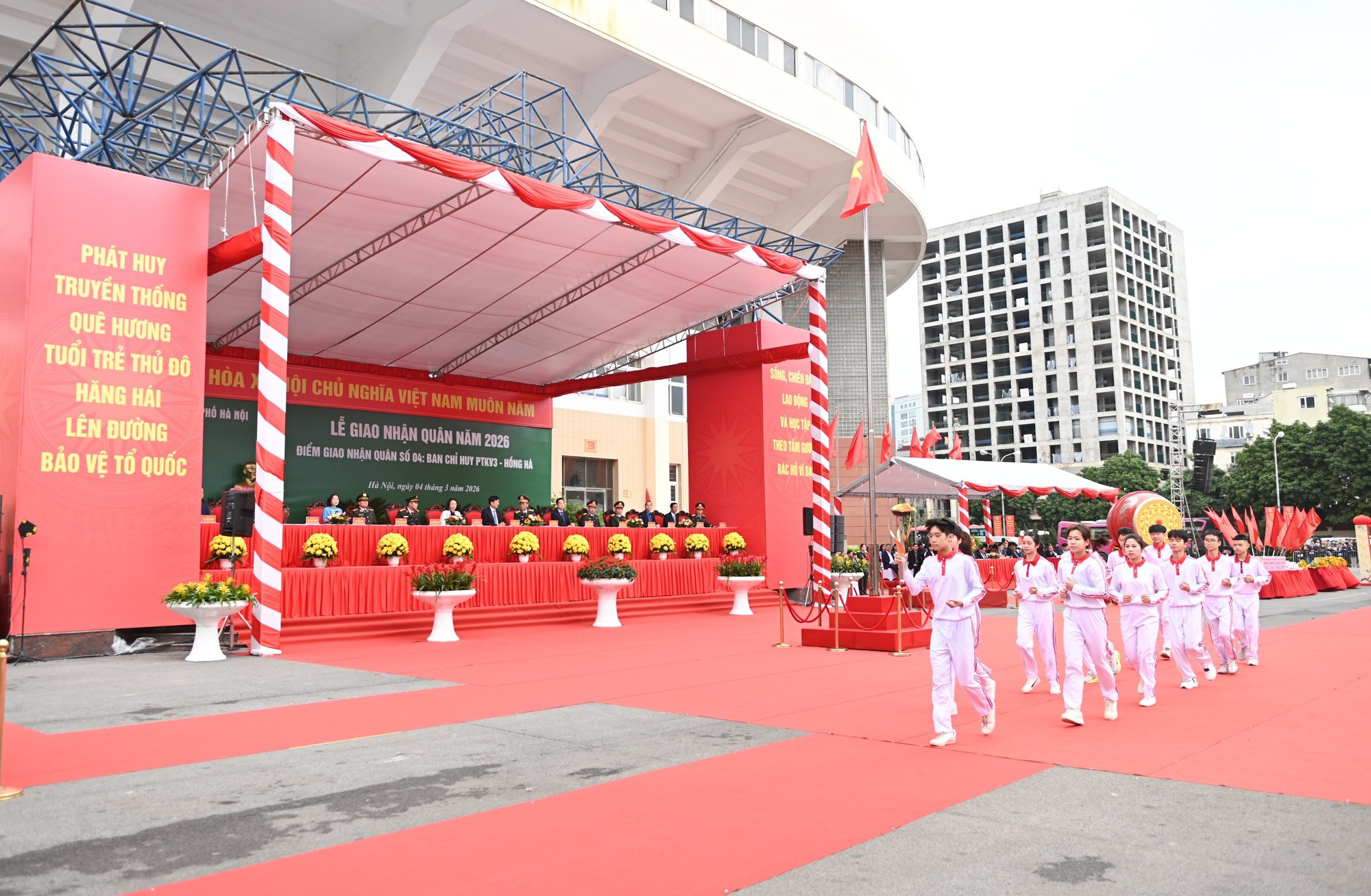 Le cortège transportant la flamme traditionnelle traverse la tribune.
