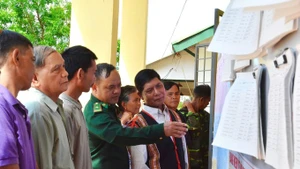 Des cadres du poste de garde-frontière de Ia Nan, avec des patriarches, guident les habitants à consulter les informations sur les candidats aux élections de l’Assemblée nationale et des conseils populaires. Photo : Baotintuc.
