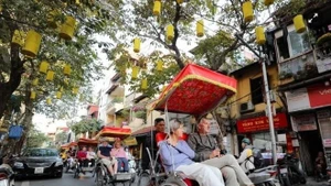 Les touristes étrangers visitent les rues en cyclo-pousse, admirant la beauté antique d'Hanoï. Photo : VNA.