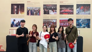 Les jeunes prennent des photos souvenirs dans l’espace de l’exposition « 95 ans sous la lumière du drapeau du Parti ». Photo : NDEL.