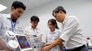 Des professeurs de la faculté de technologie électronique de l'université industrielle de Hô Chi Minh-Ville encadrent les étudiants dans leurs études et leurs recherches au laboratoire IoT et IA. Photo : VNA.