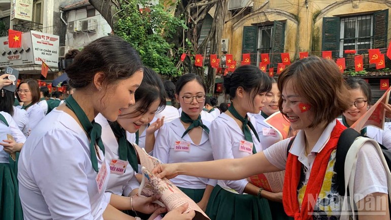 Des Vietnamiens de l’étranger reçoivent le supplément spécial du journal Nhân Dân des mains d’un reporter. q2.jpg