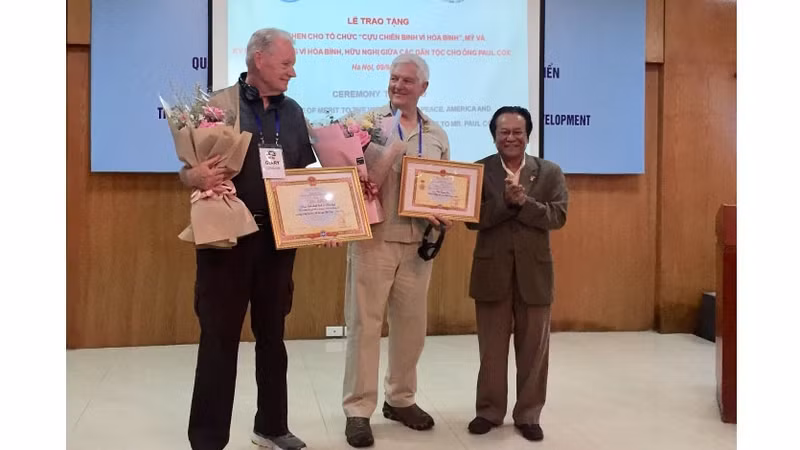 Paul Cox (au centre) lors de la remise de l’Insigne « Pour la paix et l'amitié entre les nations ». Photo : baoquocte.vn.
