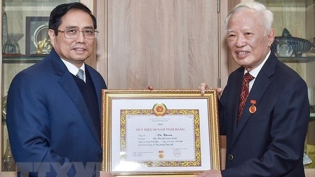 Le Premier ministre Pham Minh Chinh (gauche) remet l'Insigne de 60 ans de membre du Parti à l’ancien secrétaire du Comité central du Parti et ancien vice-Premier ministre Vu Khoan. Photo : VNA.