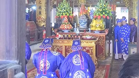 Les villageois en costume traditionnel se réunissent dans la cours de la maison commune. Photo: CVN.