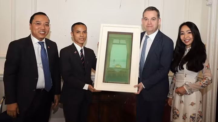 L'ambassadeur du Vietnam au Royaume-Uni, Nguyên Hoàng Long (premier, à gauche) offre une peinture au ministre d'État britannique au Cabinet Office, Nigel Adams (deuxième, à droite). Photo : VNA.