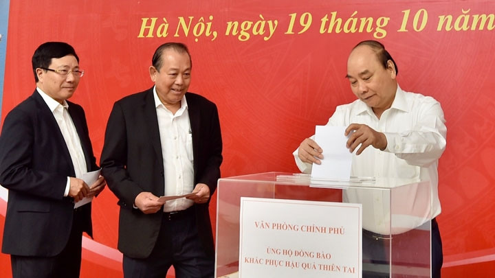 Le Premier ministret Nguyên Xuân Phuc, le Vice-Premier ministre permanent Truong Hoa Binh et le Vice-Premier ministre et ministre des Affaires étrangères Pham Binh Minh font des dons pour soutenir les personnes touchées par les inondations dans la région centrale. Photo : VGP.