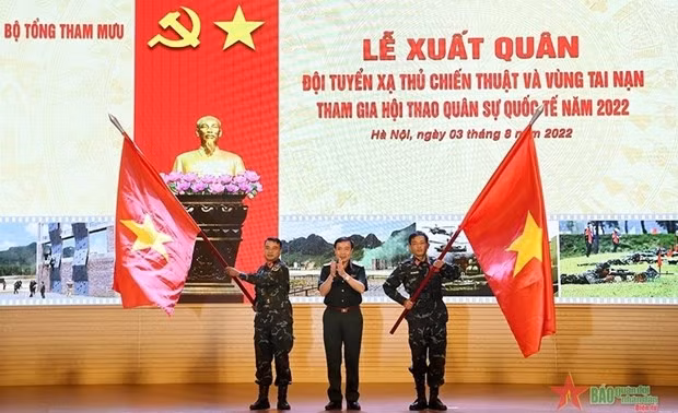 Le général Thai Van Minh, chef du Service de formation militaire (au milieu), remet des drapeaux nationaux à des représentants des deux équipes. Photo : qdnd.vn