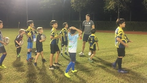Le rugbyman François Trinh Duc joue l’entraîneur avec les élèves de l’école Marguerite Duras au rugby sur le terrain de rugby Sala. Photo : VNA.
