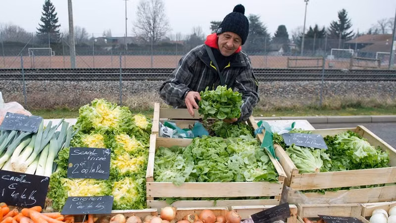 Dans un marché en plein air en Haute-Savoie, en France, un homme vend des légumes produits en respectant les normes recommandées par l’OMS. Photo OMS.