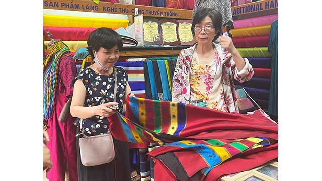 Une visiteuse achète des produits au village de la soie de Van Phuc. Photo : kinhtedothi.vn