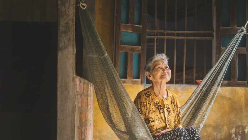 Une vieille dame assis sur un hamac de son porche. Photo : Andrew Faulk/Travel + Leisure.