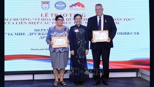 Nguyên Phuong Nga (au milieu), présidente de la VUFOA, remet l'insigne à Aleksei Vladimirovich Popov et à Natalia Borisovna Zolkina. Photo: VNA