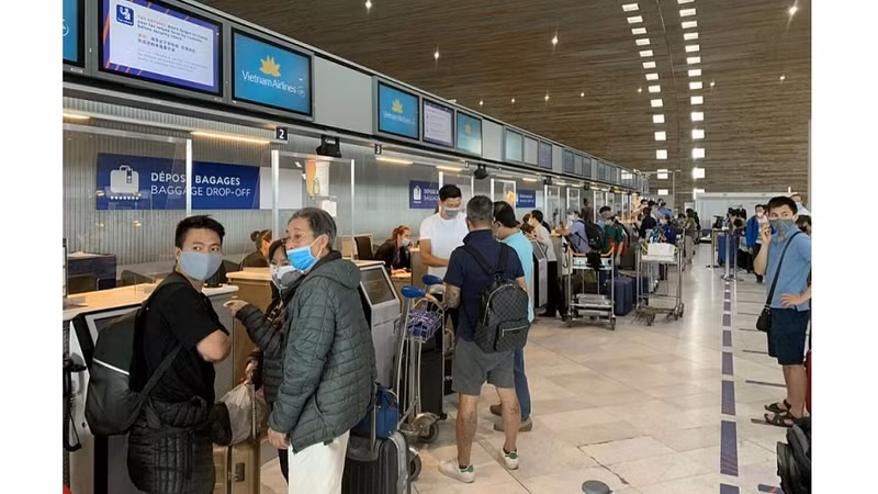 Des passages du vol de Vietnam Airlines réalisent des formalités nécessaires à l’aéroport en France avant de monter à bord. Photo : baoquocte.vn.