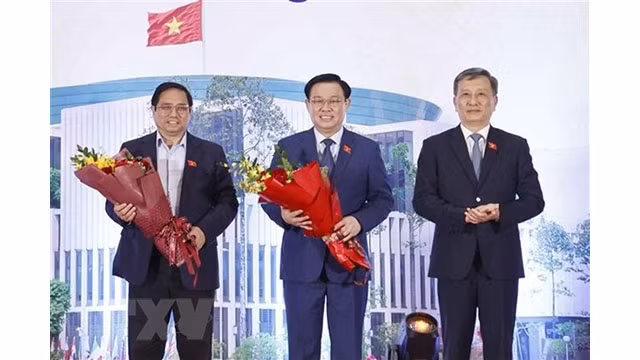 Le président de la Commission des sciences et technologies et de l’environnement de l'Assemblée nationale, Lê Quang Huy (à droite), offre des fleurs au Premier ministre Pham Minh Chinh (à gauche) et au Président de l'Assemblée nationale Vuong Dinh Huê (au milieu). Photo : VNA.