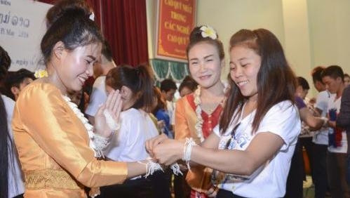 Le fait de s’attacher des fils de coton «porte-bonheur» au poignet, un rite traditionnel lors du Boun Pimay. Photo: VNA.