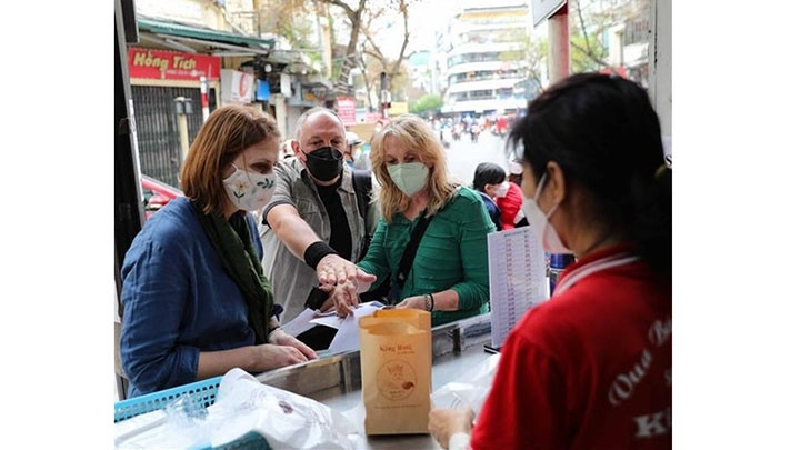 Les touristes étrangers dégustent la cuisine dans le Vieux quartier de Hanoi. Photo : VNA.
