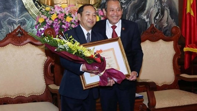 Le président de la Cour populaire suprême du Vietnam, Truong Hoa Binh, remet l'insigne «Pour l'œuvre de la Cour populaire suprême du Vietnam» au vice-président de la Cour populaire suprême du Laos, Khampha Sengdara. Photo: VNA.