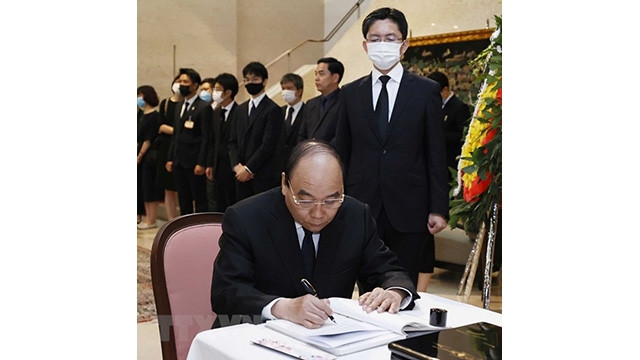 Le Président de la République, Nguyên Xuân Phuc, écrit sur le registre de condoléances à l'ambassade du Japon. Photo : VNA. 