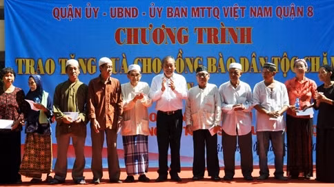 Le vice-premier ministre Truong Hoa Binh (au centre) offre des cadeaux à des Cham du 1er quartier, 8e arrondissement, Hô Chi Minh-Ville. Photo: VGP.
