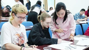 Des étudiants internationaux découvrent l’art de la calligraphie lors du programme « Têt vietnamien pour les étudiants internationaux » à l’Université pédagogique relevant de l'Université de Da Nang. Photo : Portail d’information électronique de la ville de Da Nang.