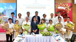 Le vice-ministre de la Santé, Tran Van Thuan, offre des fleurs et un certificat de mérite à l’équipe qui réalise une intervention fœtale sur une patiente singapourienne. Photo : nhandan.vn