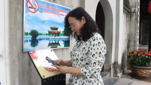 Des visiteurs scannent un code QR pour découvrir le parcours de visite numérisé au site historique du temple Do. Photo : VNA.