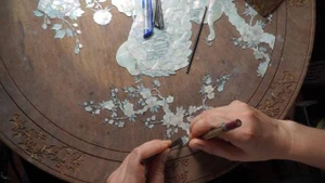 Un artisan ajuste les éléments de nacre avant la gravure – Yen Van. Photo : laodong.vn
