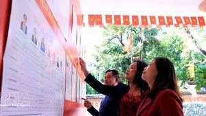 Des électeurs se rendent à un bureau de vote local pour consulter la liste des candidats à la 16e Assemblée nationale et aux conseils populaires à tous les niveaux pour le mandat 2026-2031. Photo : VNA 