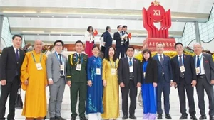La vice-ministre des Affaires étrangères Lê Thị Thu Hằng pose pour une photo avec une délégation de Vietnamiens à l'étranger exemplaires venus assister au XIᵉ Congrès national d’émulation patriotique, le 27 décembre 2025. Photo : baoquocte.vn