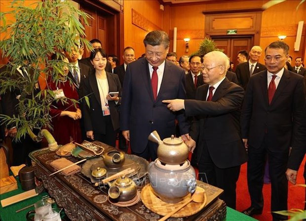 Le Secrétaire général Nguyên Phu Trong et le Secrétaire général et Président chinois Xi Jinping écoutent présenter sur le thé. Photo : VNA.