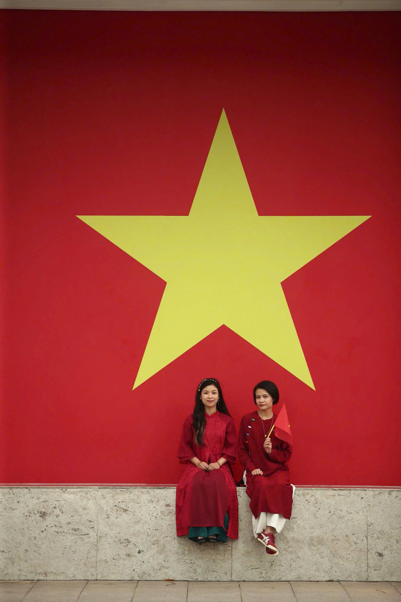 Deux touristes prennent une photo avec le drapeau national. Photo : VGP.