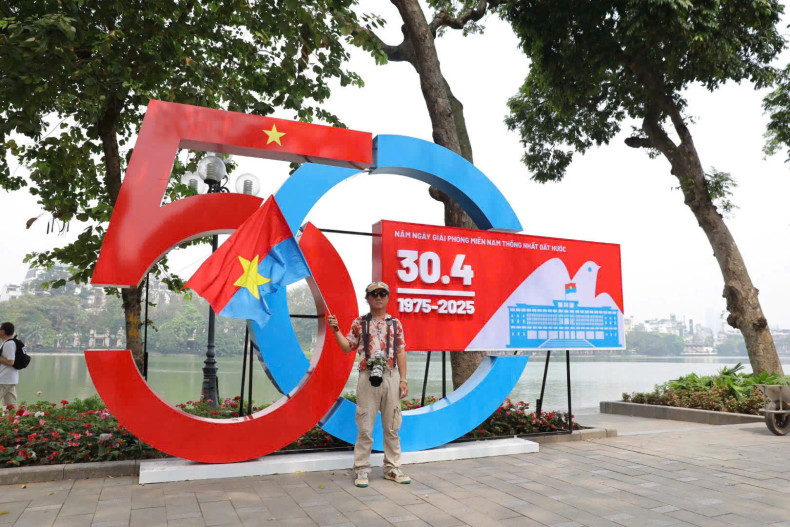 Un touriste portant le drapeau du Front de libération nationale du Sud-Vietnam prend une photo à côté du mannequin au lac Hoan Kiem. Photo : VGP.