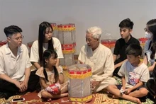 L’artisan Nguyên Van Quyên (centre) présente la fabrication d’une lanterne "keo quân" au Musée d’ethnographie du Vietnam, à Hanoi. Photo : VNA. 