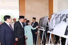 Le Premier ministre Pham Minh Chinh (à gauche) et son homologue malaisien, Anwar Ibrahim, visitent une exposition de photo de l'Agence vietnamienne d'Information. Photo : VNA.
