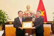 Le vice-ministre permanent des Affaires étrangères Nguyên Minh Vu (à droite) remet l’insigne «Pour la cause des affaires étrangères du Vietnam» au directeur général de Samsung Vietnam, Choi Joo Ho, à Hanoi, le 13 février. Photo : VNA.