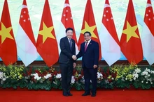 Le Premier ministre Pham Minh Chinh (à droite) et son homologue singapourien Lawrence Wong se serrent la main, à Hanoï, le 26 mars. Photo : VNA