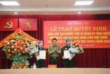 Le vice-ministre de la Sécurité publique Luong Tam Quang présente la décision du président à deux agents de la Sécurité publique d'effectuer des missions de maintien de la paix des Nations Unies. Photo : NDEL.