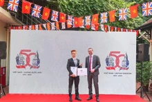 L’ambassadeur britannique Iain Frew (à droite) et le gagnant du concours de création du logo pour célébrer le 50e anniversaire de l’établissement des relations diplomatiques entre le Royaume-Uni et le Vietnam, Ngô Quang Trung. Photo : VNA.