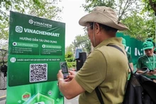Les gens scannent directement le code QR de la plateforme de commerce électronique VinachemMart dans la rue piétonne du lac Hoàn Kiêm. Photo : VNA.