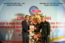Un représentant du Comité de liaison des volontaires et experts militaires vietnamiens (à droite) offre un annuaire du 75e anniversaire anniversaire de la Journée traditionnelle des soldats volontaires et experts vietnamiens au Lao au consul général du Laos à Da Nang. Photo : VNA