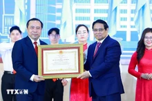 Le Premier ministre Pham Minh Chinh remet l'Ordre du Travail de première classe, décerné par le président de la République, à l'Université nationale de Hô Chi Minh-Ville. Photo : VNA.