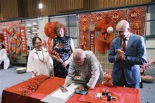 Le gouverneur du Territoire du Nord de l'Australie, Hugh Heggie (gilet bleu), observe la calligraphie lors de l'événement. Photo : VNA