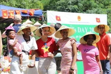 Des amis sud-africains prenant des photos souvenirs avec des chapeaux coniques vietnamiens lors de l'événement. Photo : VNA 