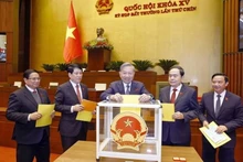 Le secrétaire général du Parti, To Lam, le président Luong Cuong, le Premier ministre Pham Minh Chinh, le président de l'Assemblée nationale Tran Thanh Man et des délégués votent lors de la séance. Photo : VNA.