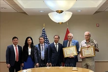 Lors de la cérémonie de remise de l’insigne « Pour la paix et l’amitié entre les peuples » à trois américains. Photo: VNA