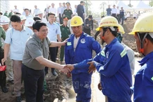 Le Premier ministre Pham Minh Chinh serre la main d'un ouvrier sur le chantier du projet de rocade 3 de Hô Chi Minh-Ville. Photo : VNA.