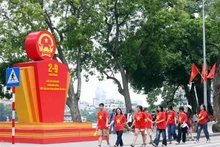 Des jeunes marchent en liesse devant un paneau célébrant la 79e Fête nationale du Vietnam, près du lac Hoàn Kiêm, à Hanoi. Photo : VNA.