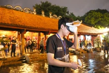 Un touriste découvre la technologie de réalité virtuelle lorsqu'il visite le Temple de la Littérature. Photo: hanoimoi
