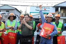 Le Premier ministre Pham Minh Chinh offre des cadeaux aux travailleurs sur le chantier de la construction d’une digue sur la rivière Cân Tho. Photo : VNA.